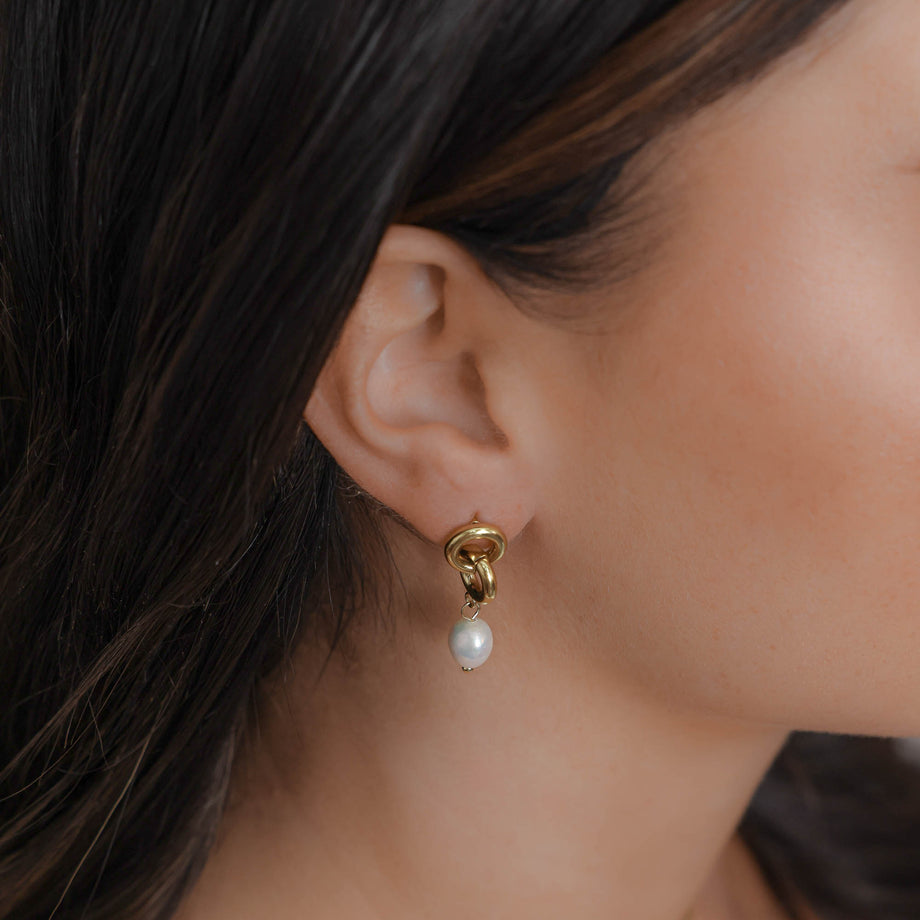 model wearing Gold chain earrings with dangling white pearls.
