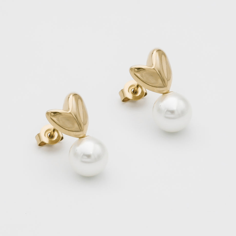 Gold heart-shaped earrings with dangling pearls.