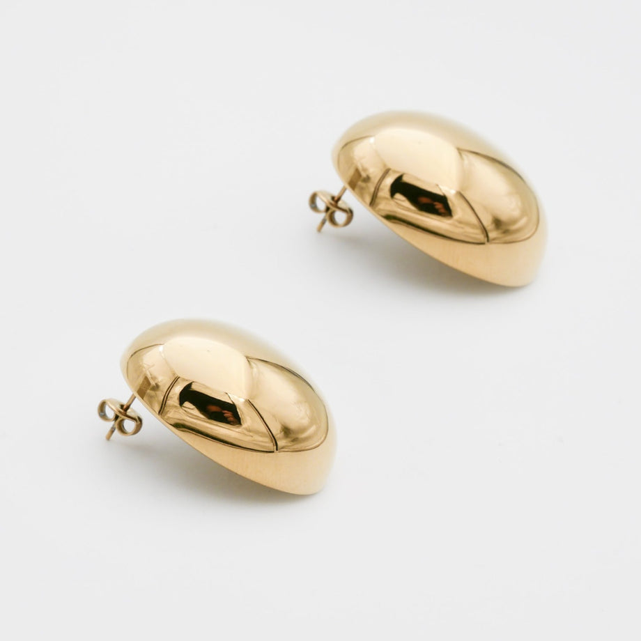 Gold spherical Maeve earrings on white background.