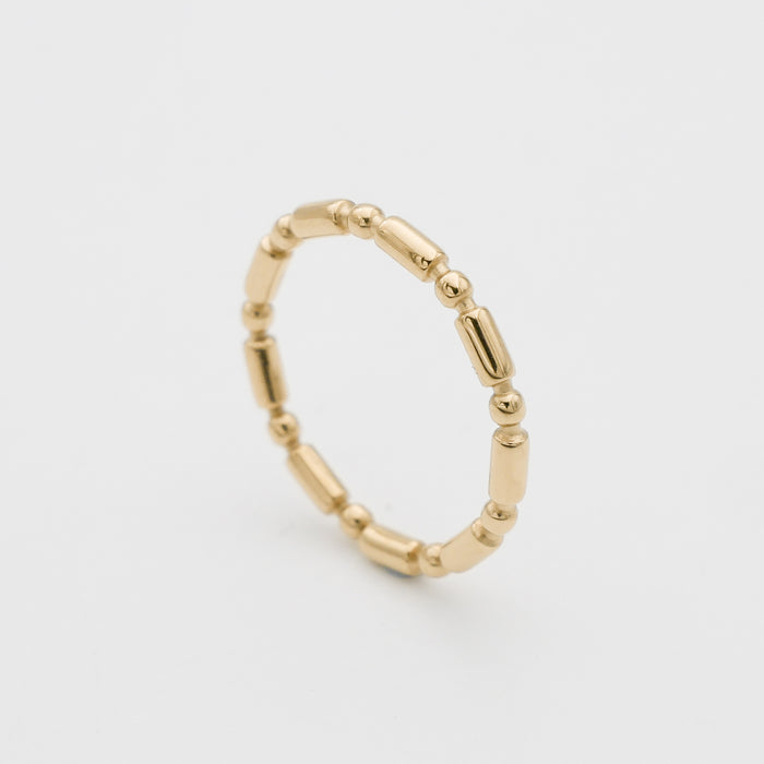 Gold beaded ring on white background.