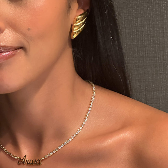 model wearing zaya statement earrings in gold from prya