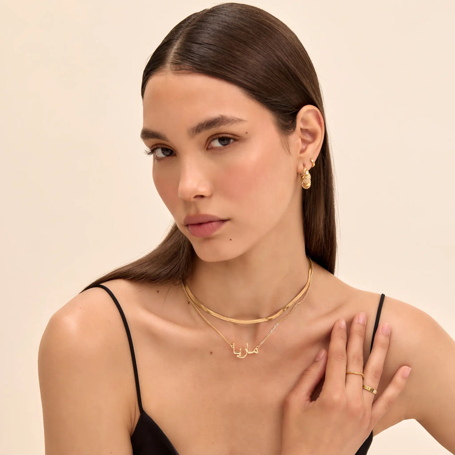 model wearing personalised arabic name necklace, herringbone necklace and hoop earrings in gold from prya