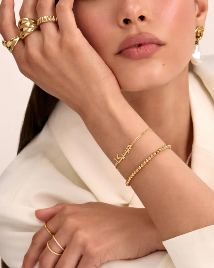 model wearing gold custom arabic name bracelet and beaded bracelet from prya