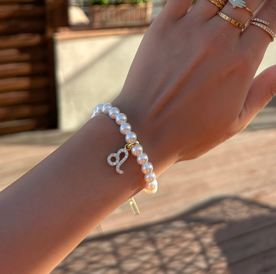 model wearing Gold-accented pearl bracelet with zodiac charm.