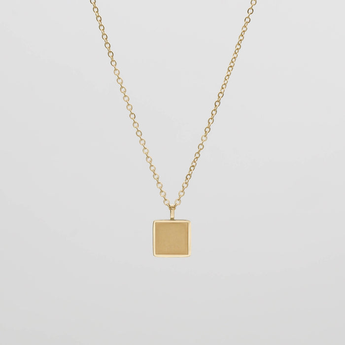 Gold necklace with a square pendant.