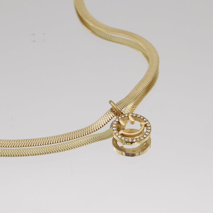 Gold necklace with a smiley face pendant.