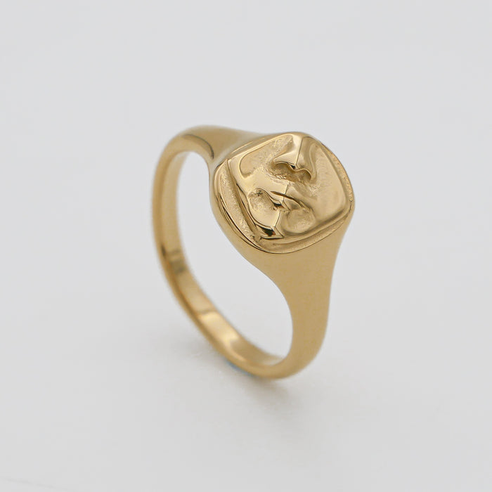 Gold ring with abstract face engraving.