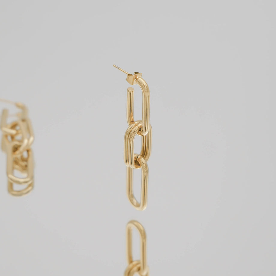 Gold chain adjustable link earrings with three links on grey background.