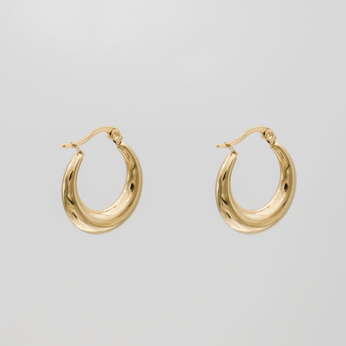Gold hoop earrings against plain background.