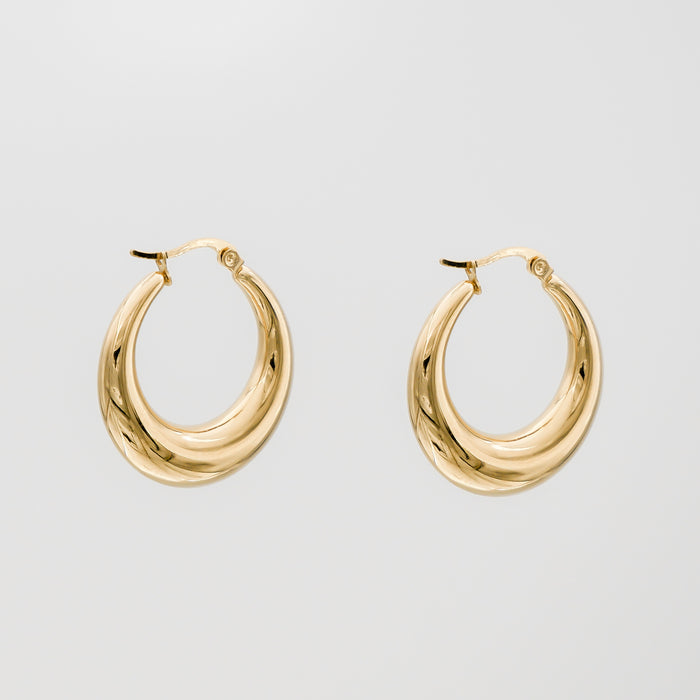 Gold hoop earrings against plain background.