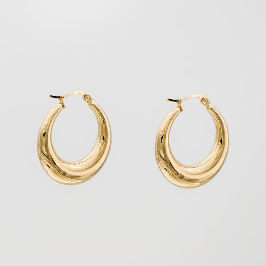 Gold hoop earrings against plain background.