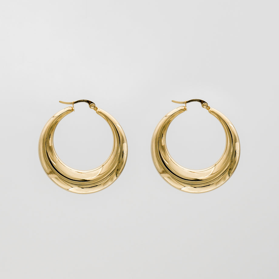 Gold hoop earrings against plain background.