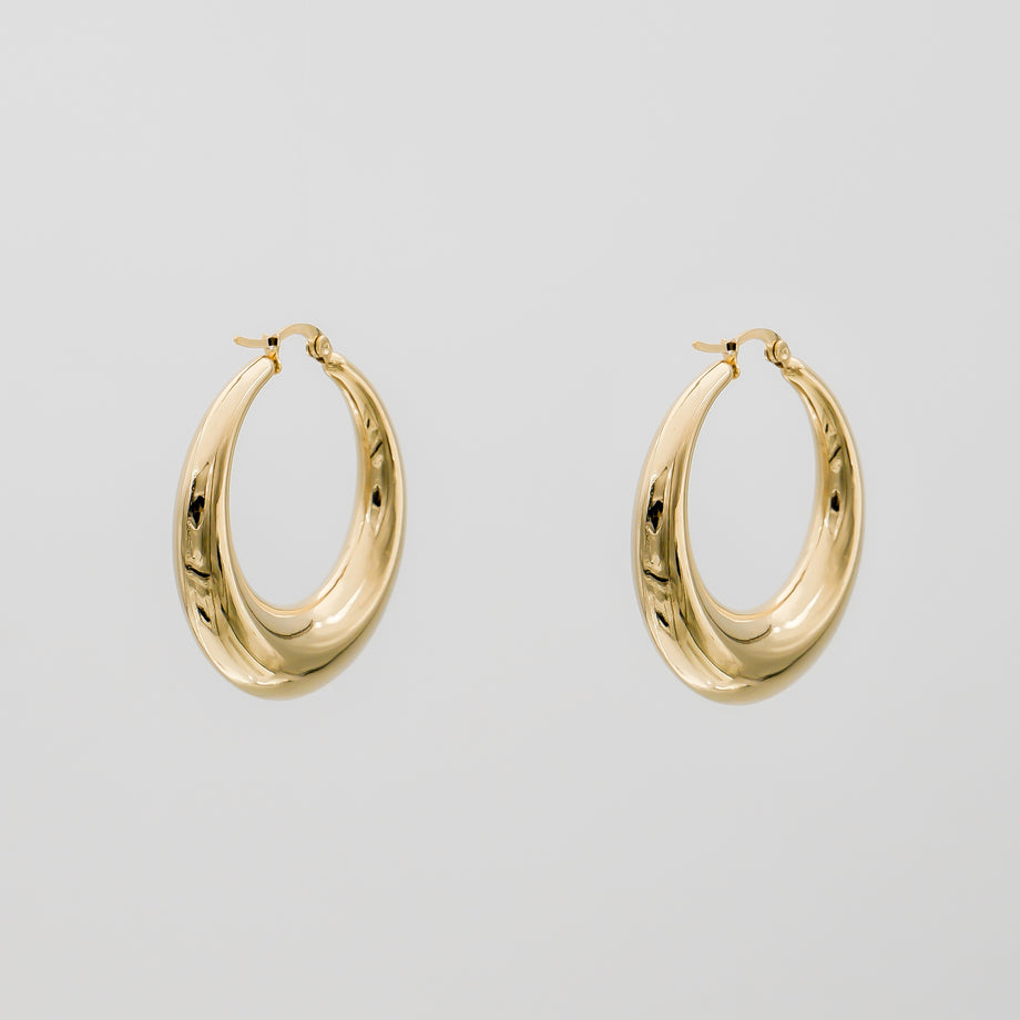 Gold hoop earrings against plain background.
