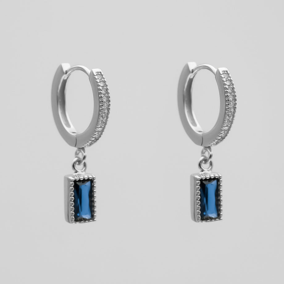 silver pave hoop earrings with blue gemstone pendants.