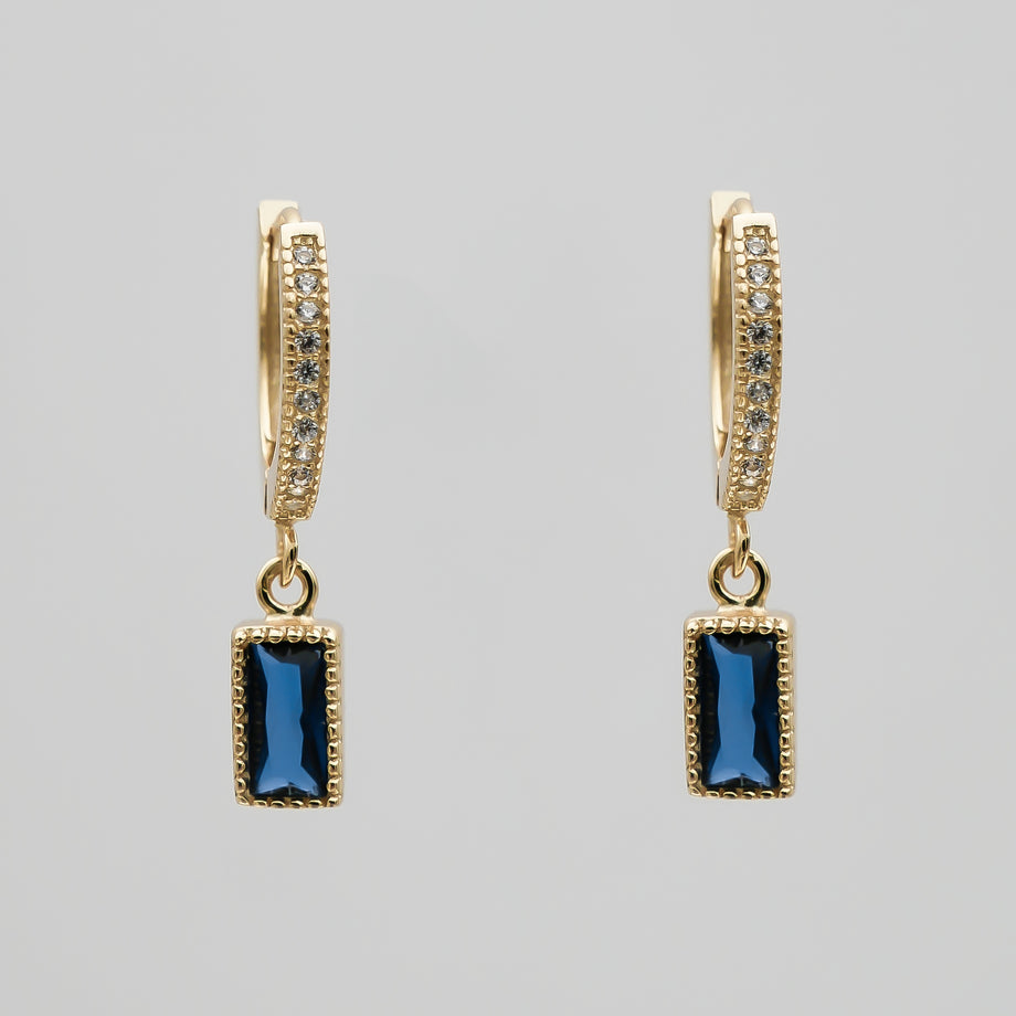 Gold pave hoop earrings with blue gemstone pendants.