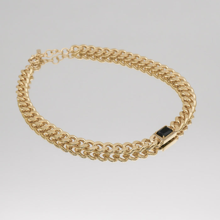 Gold chain necklace with a black gemstone.