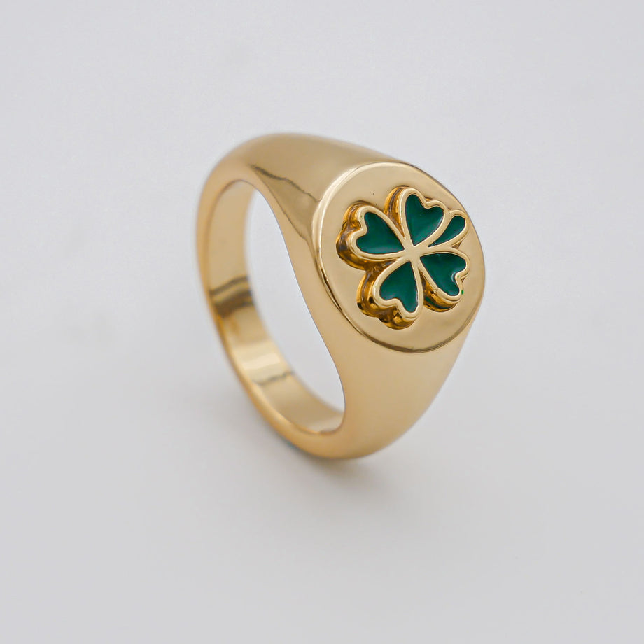 Gold ring with green clover design.