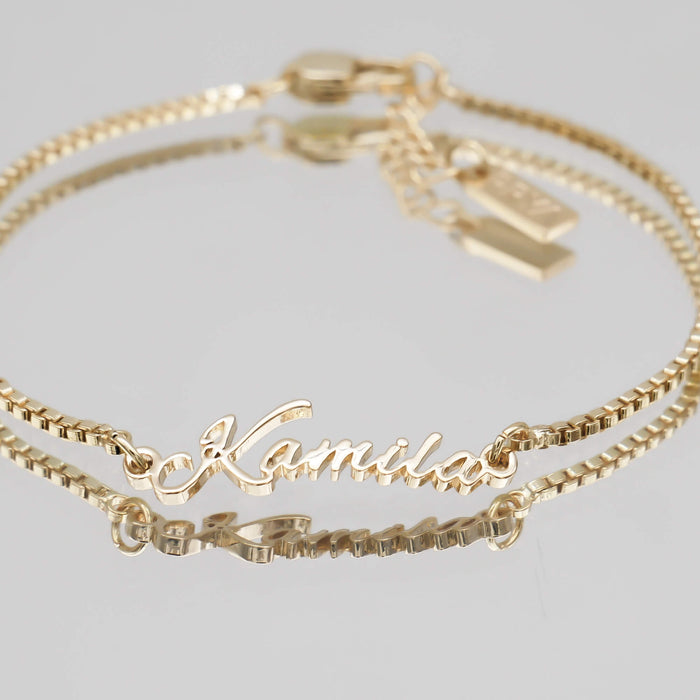 Gold name bracelet with double chain.