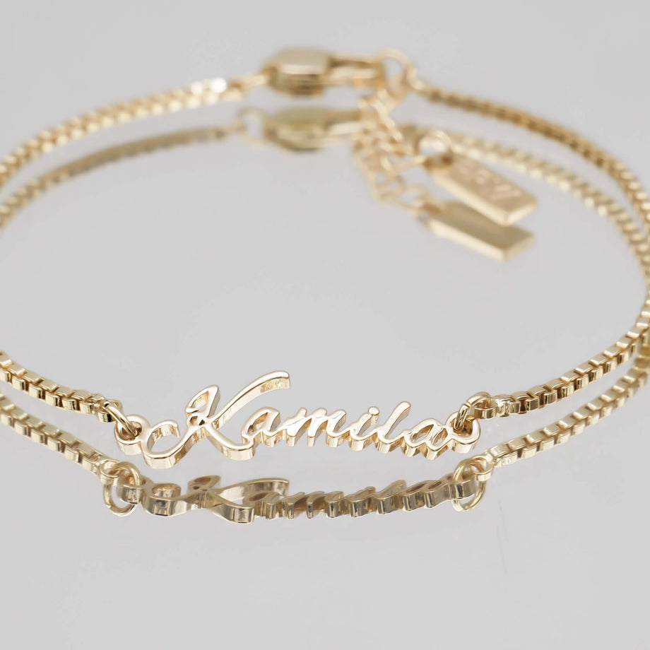 Gold name bracelet with double chain.