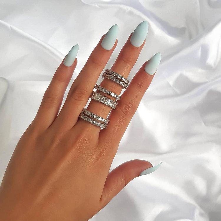 Several Cubic Zirconia Rings on a woman's hand with light blue nail polish