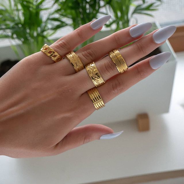 How to wear rings on multiple fingers - Woman's hand with several gold rings on it