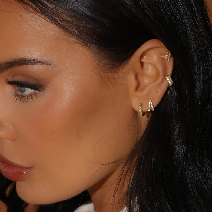 model wearing  stack of cz earrings including huggies, and cuffs from prya