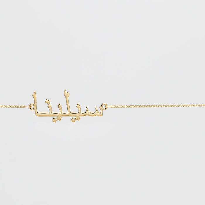 Gold Arabic script belly chain on white background.