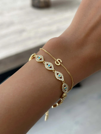 model wearing 18k gold plated bracelets from prya, personalised initial bracelet and evil eye bracelet