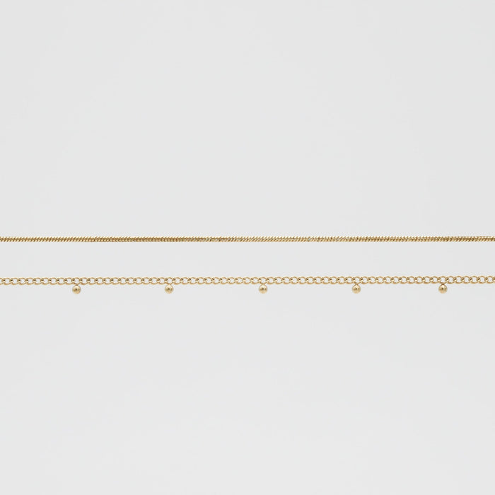 Two delicate gold belly chains on white background.