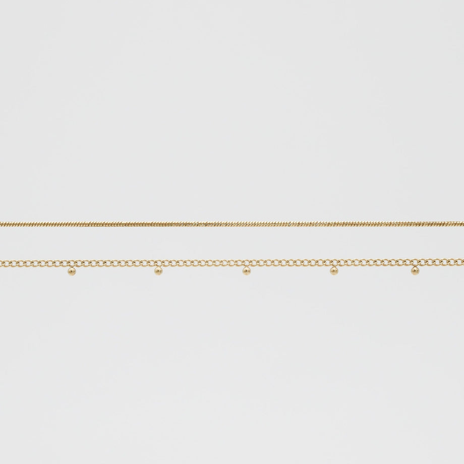 Two delicate gold belly chains on white background.