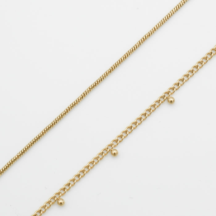 Two delicate gold belly chains on white background.