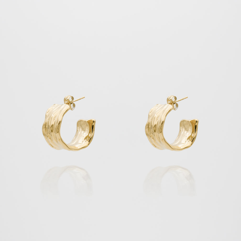 Gold textured hoop earrings on white background.