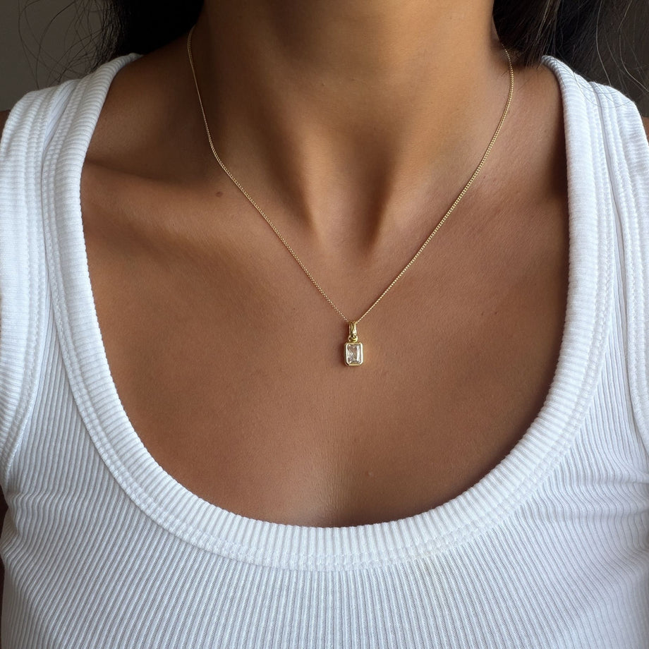 Model wearing the april emerald cut birthstone necklace in gold from prya
