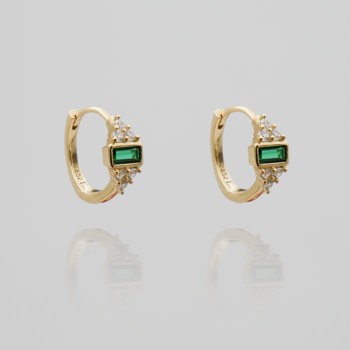 Gold huggie earrings with green gemstones.