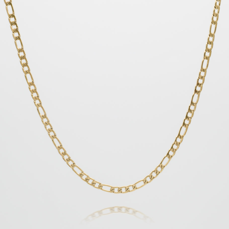 Gold Figaro chain necklace against white background.