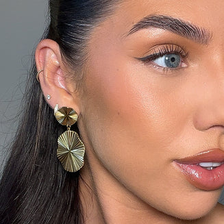 model wears Hina Gold Drop Earrings, crafted in 18k gold plated stainless steel, feature a radiant design that is reminiscent of the sun from prya