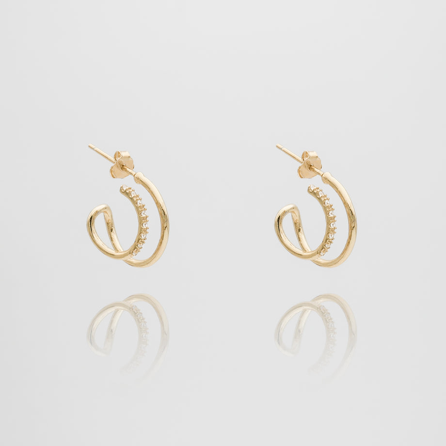 Gold earrings with spiral design and small gems.