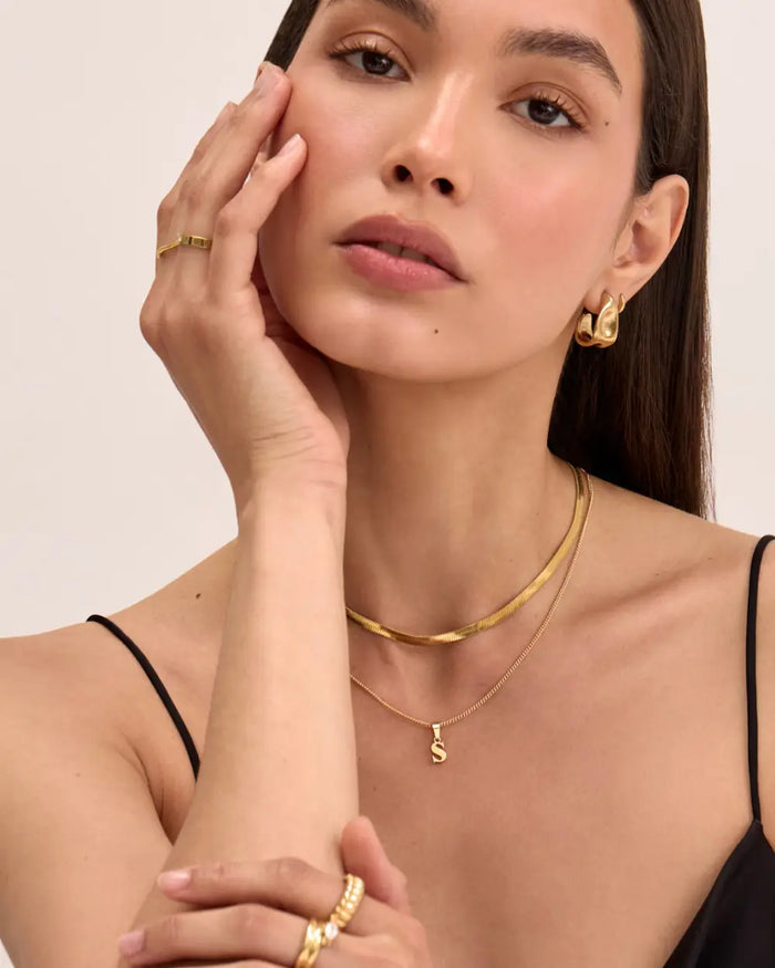 model wearing 18k Gold plated initial necklace, herringbone necklace and earrings and rings from prya, 