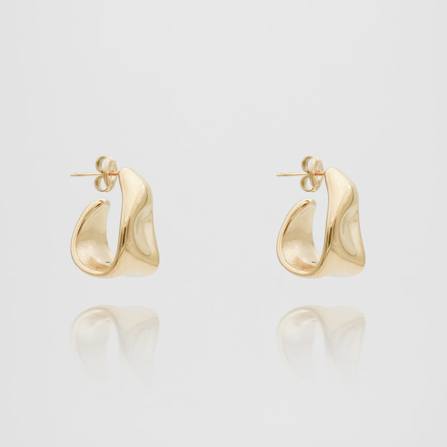 Gold abstract hoop earrings on white background.