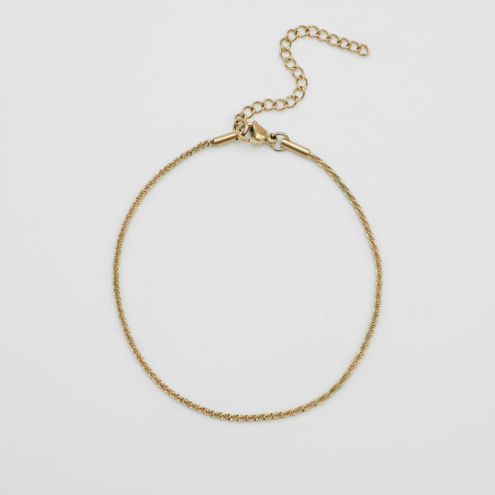 Gold anklet with adjustable chain on white background.