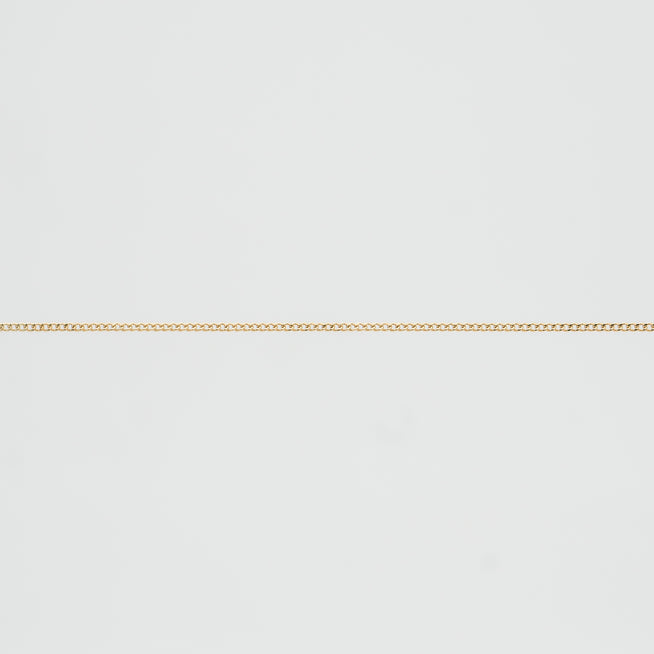 Thin gold chain on white background.
