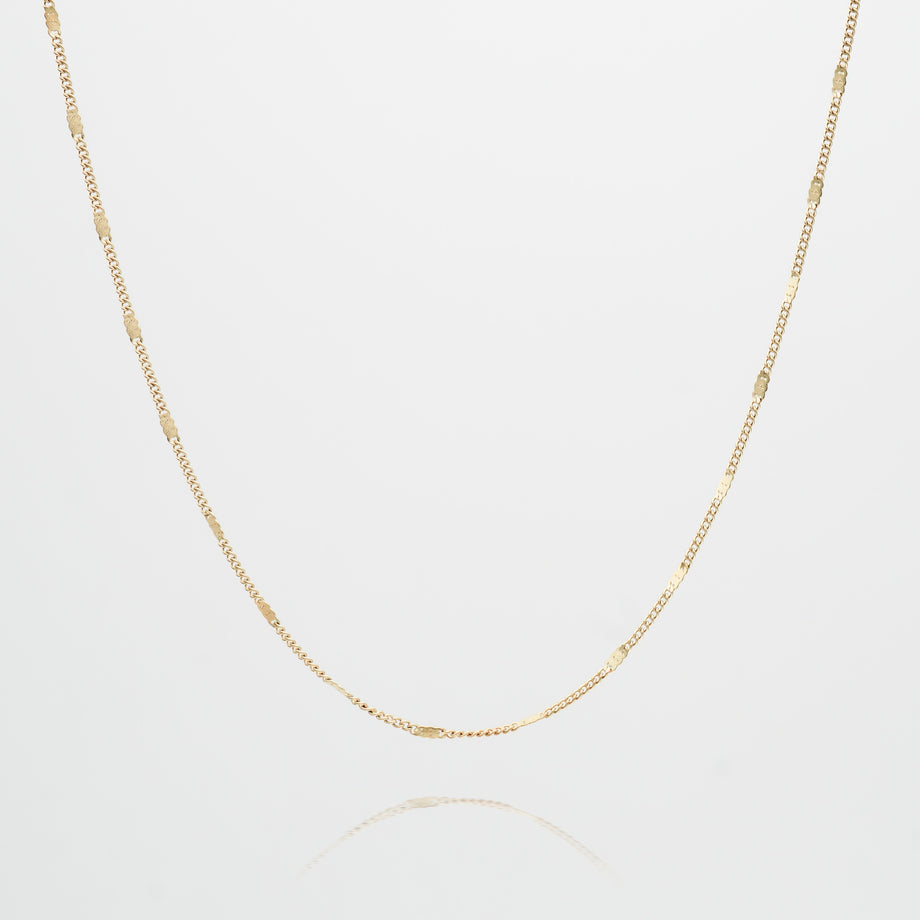 Delicate gold chain necklace on white background.