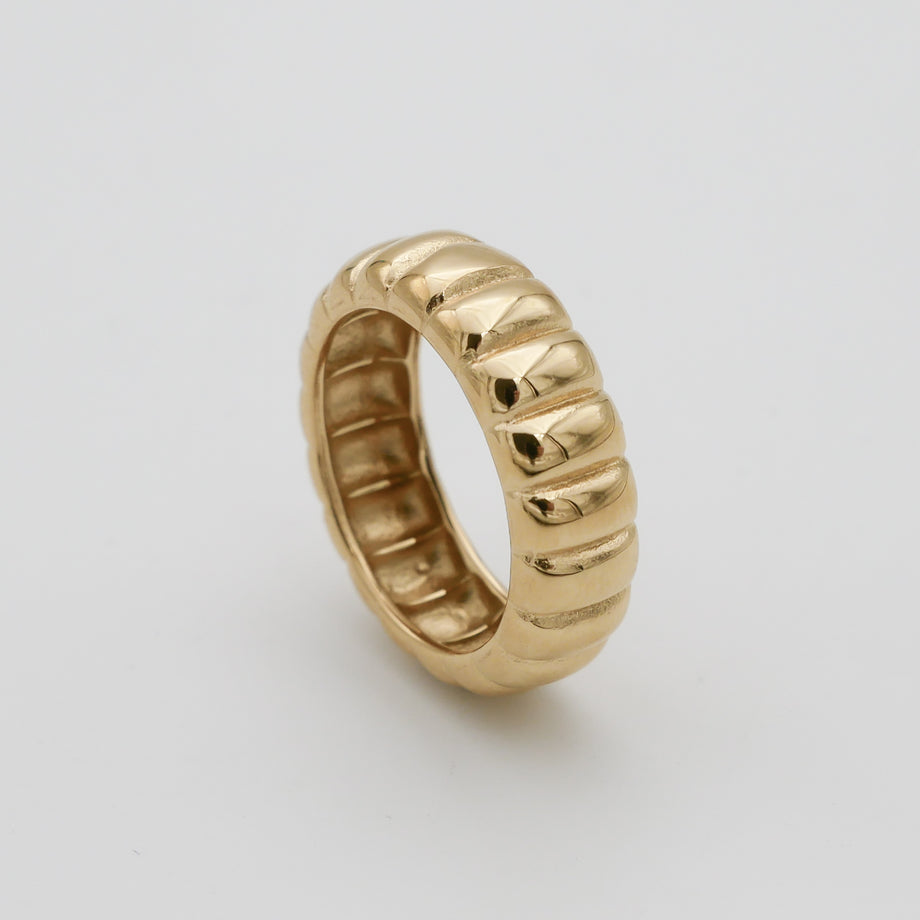 Gold ridged band ring on white background.