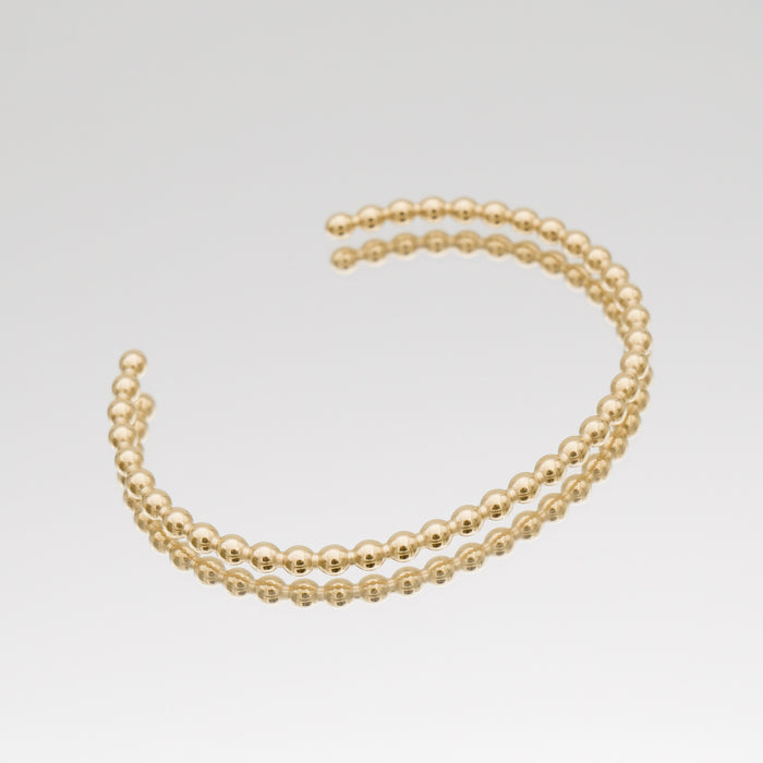 Gold double-beaded bracelet on white background.