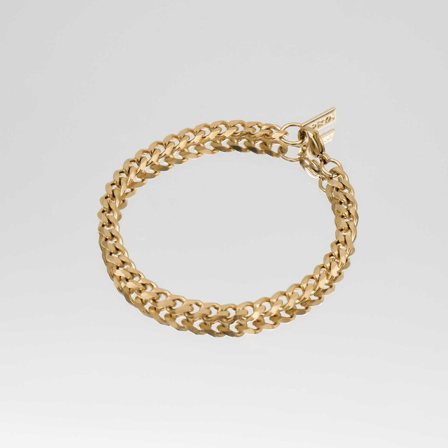 Gold chain bracelet on grey background.