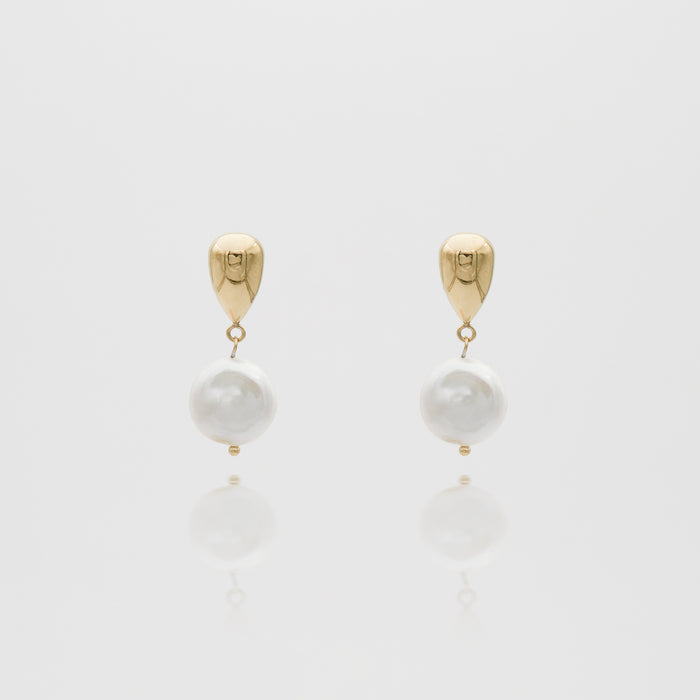 Gold and pearl drop earrings on white background.