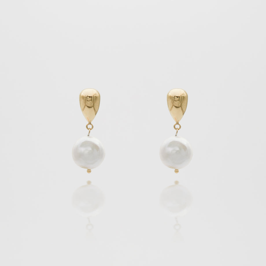 Gold and pearl drop earrings on white background.