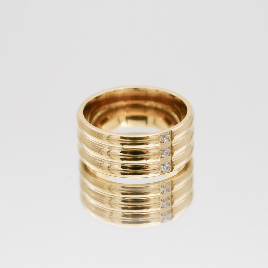 Gold ring with diamond accents, reflective surface.