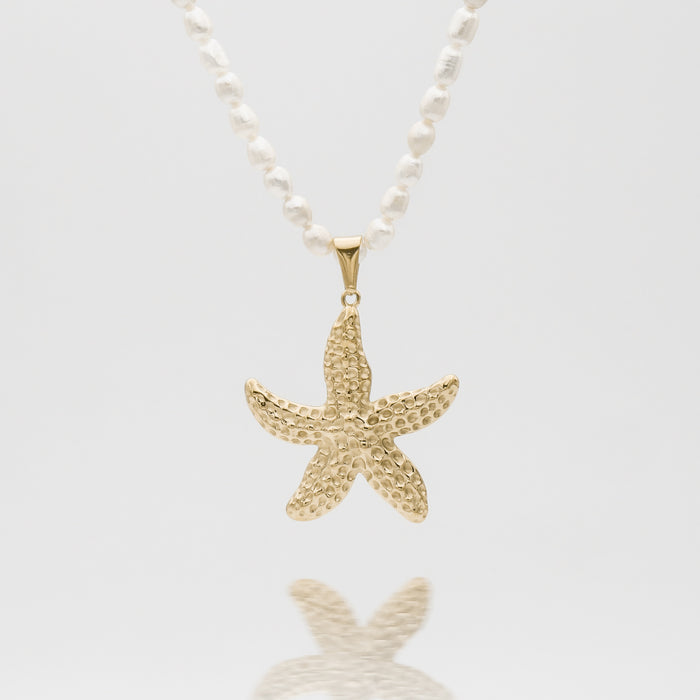 Gold starfish pendant on pearl necklace.