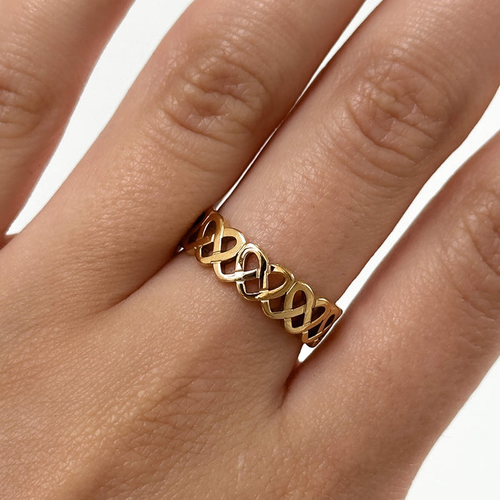 model wearing Hallie Ring features a striking gold plated band with a Celtic-inspired design, adorned with a classic love knot from Prya